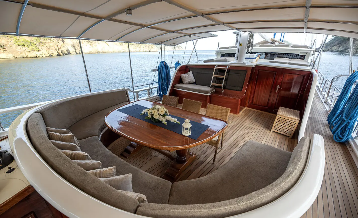 Kayhan 5 yacht charter: teak deck, round seating, steering helm, sunset on calm sea