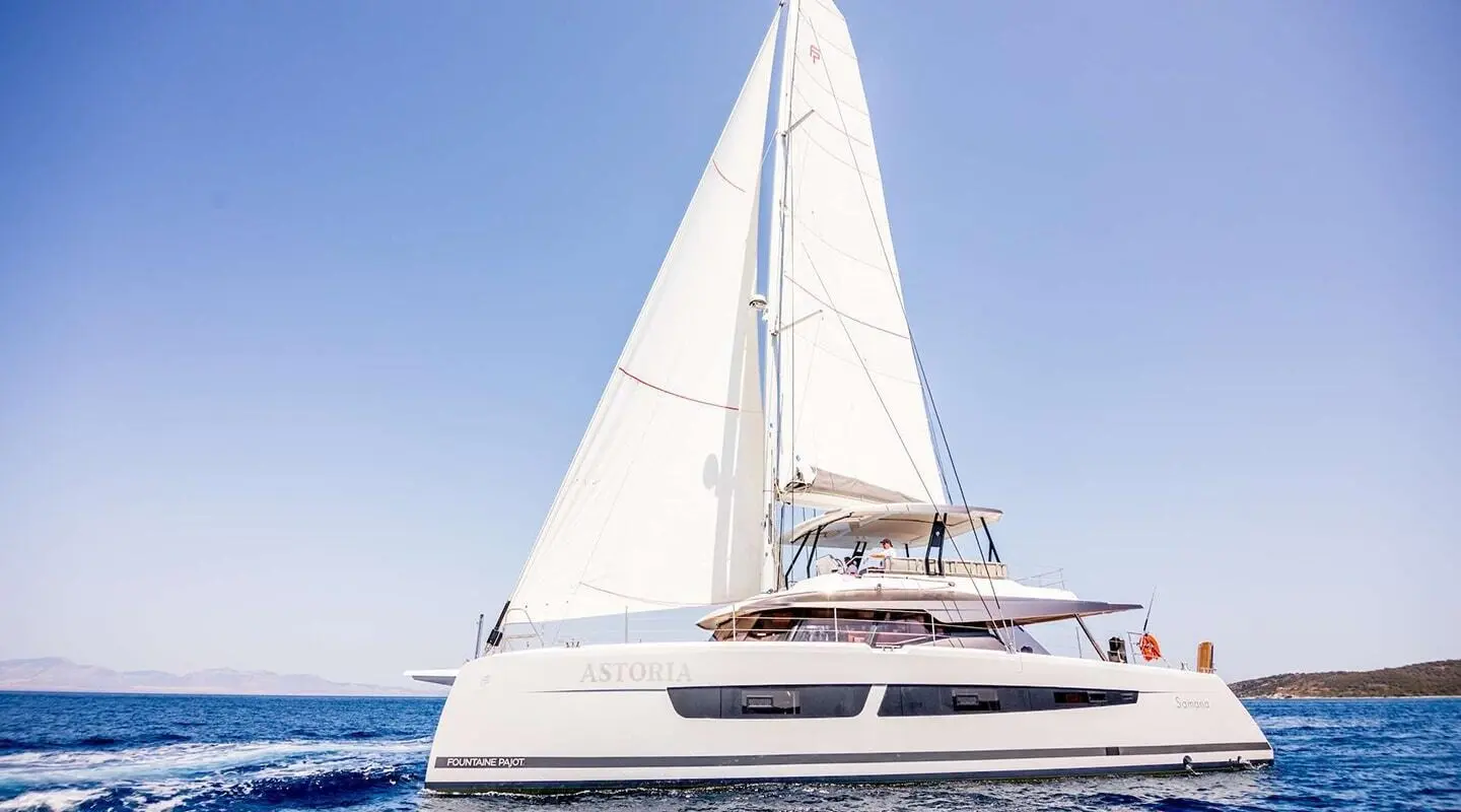 Astoria motor yacht sailing, white hull, sails raised, blue sea background