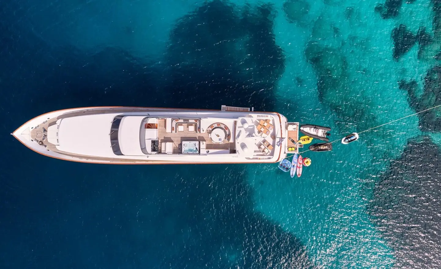 Top-down view of Mobius yacht anchored in clear blue water at sunset