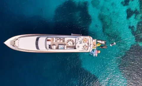 Top-down view of Mobius yacht anchored in clear blue water at sunset
