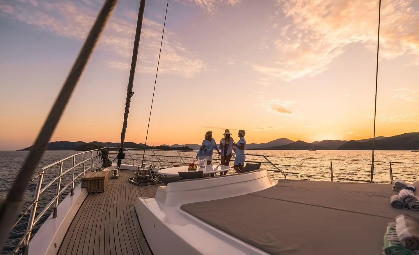 Three women chatting on the deck of a luxury yacht at sunset