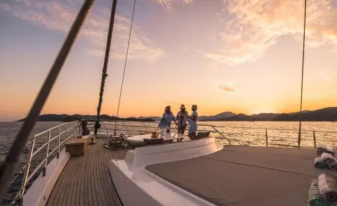 Three women chatting on the deck of a luxury yacht at sunset