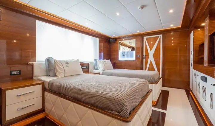 Twin cabin aboard yacht Long Island with two beds, wooden paneling, and closet