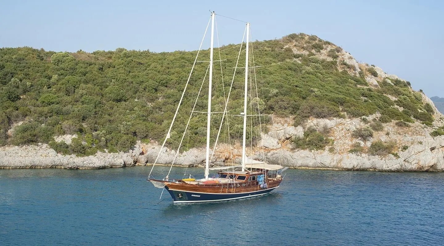 Samarkand luxury gulet anchored near rocky coastline at sunset harbor