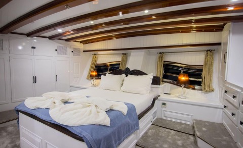 Bedroom aboard with white cabinets and wooden beam ceiling on deck
