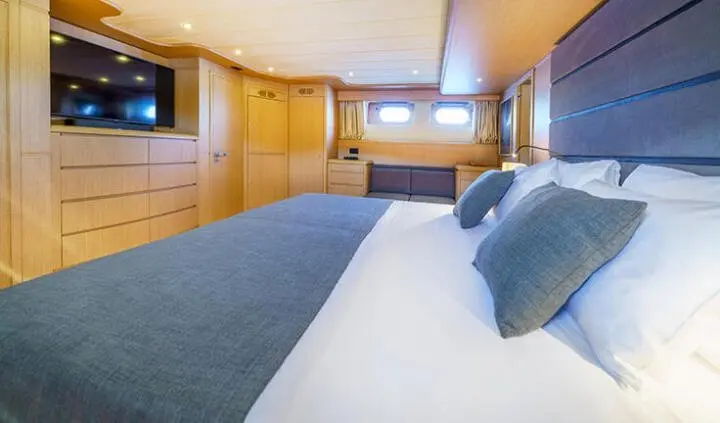 Master cabin with large bed, blue bedding, wooden panels, and an ensuite