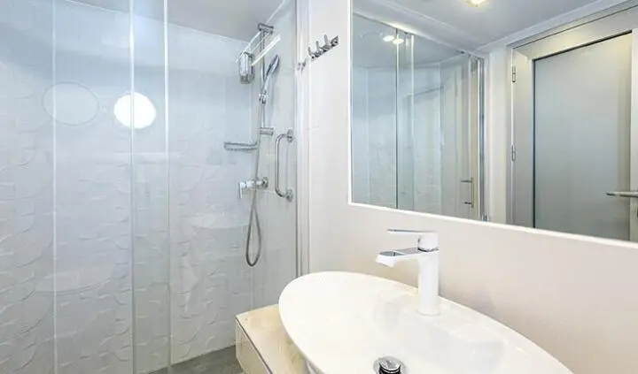 Yolo yacht cabin interior with glass shower, white sink, and modern fixtures