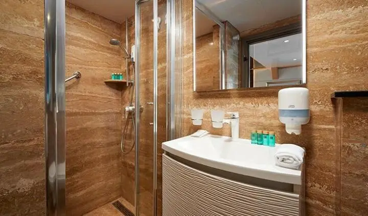 Queen Eleganza cabin bedroom: wood textures, bed, and bathroom visible.