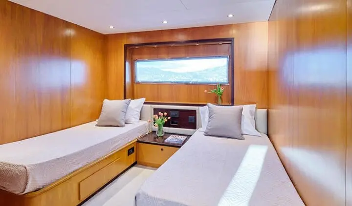Twin cabin interior on Mobius yacht showing bed, seating, and built-in wood cabinetry