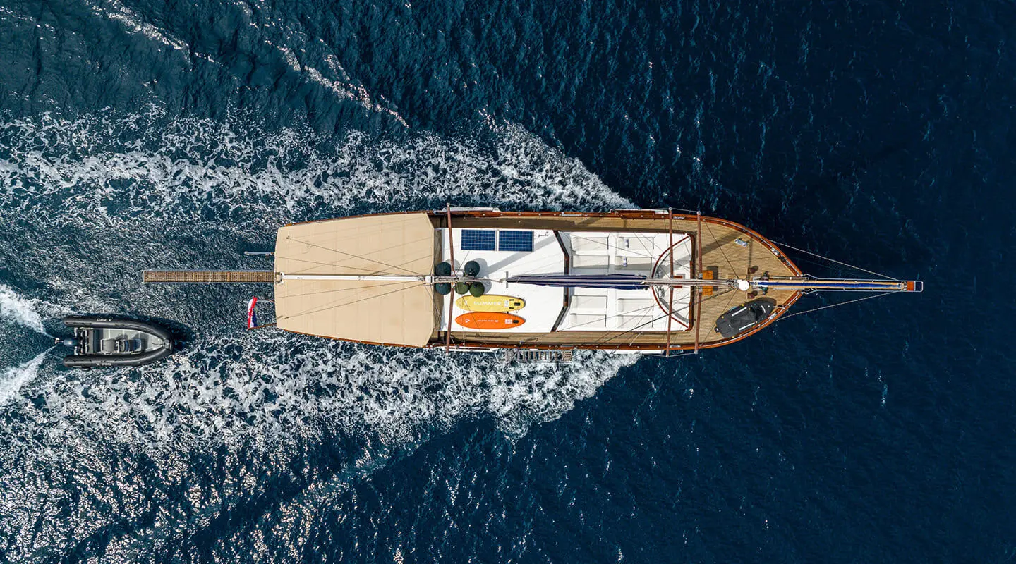 A small luxury gulet yacht named Eleganza sails coastal blue water at sunset