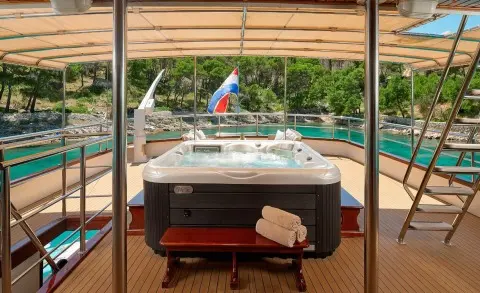 Luna yacht on open deck with a jacuzzi, sea and shoreline in the background