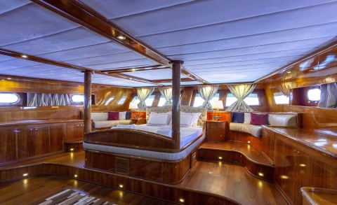 Wooden yacht interior with a large bed and plush cushions on deck
