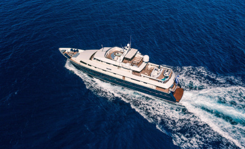 Magix luxury motor yacht cruising blue sea, aerial view showing deck lounges and aft seating