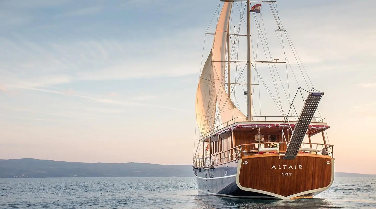 Altair gulet viewed from the rear on the water with a wooden hull and deck