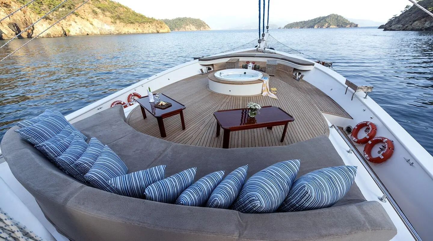Kayhan Kaptan yacht deck furnished with circular seating and a central table at sunset