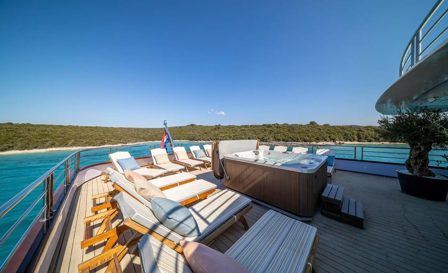 Olimp yacht deck with sun loungers and a hot tub overlooking turquoise sea