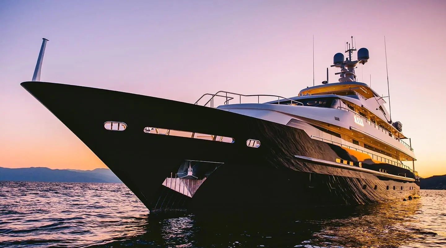 Xana motor yacht anchored at sunset with dark hull and orange reflections