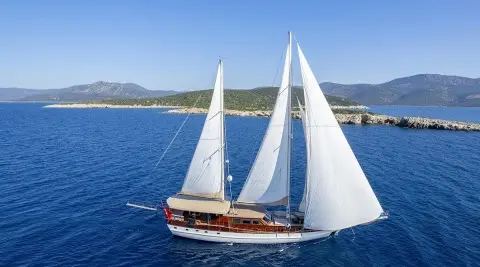 Yacht Arabella gulet sails on blue sea with clear horizon and coastline