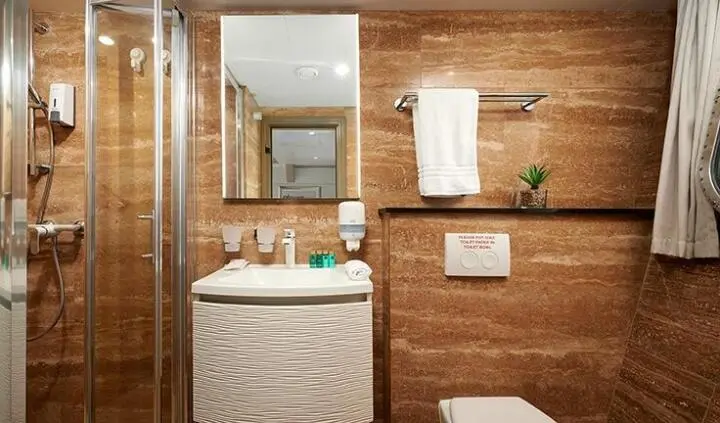 Queen Eleganza master cabin with bed, wooden walls, and ensuite door