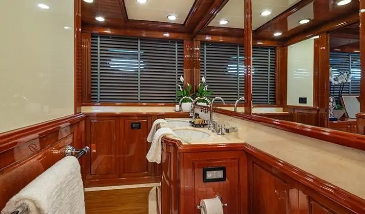 View of a wooden yacht cabin with sink, mirror, and polished cabinetry