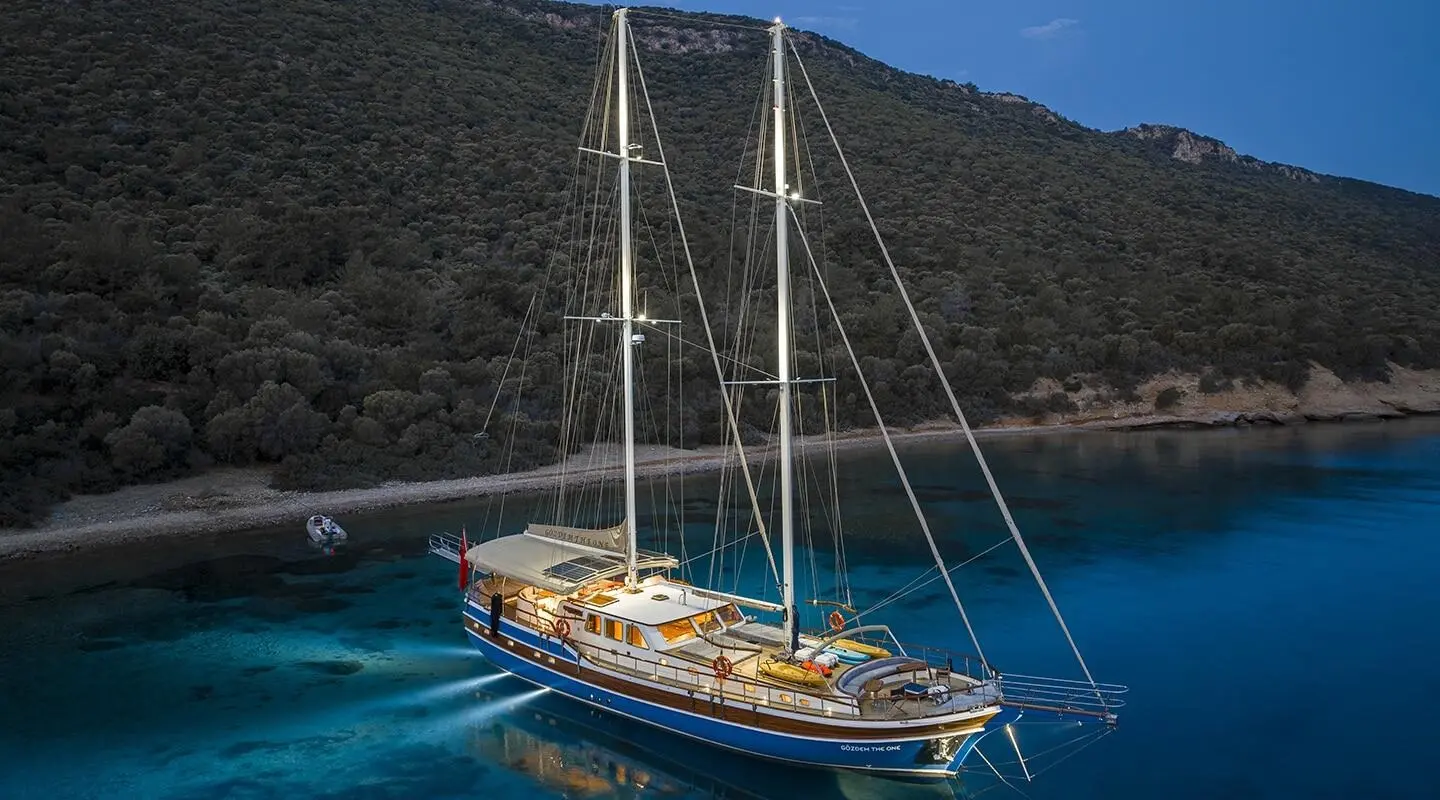 Gozdem The One yacht anchored near rocky coastline at sunset with sails down