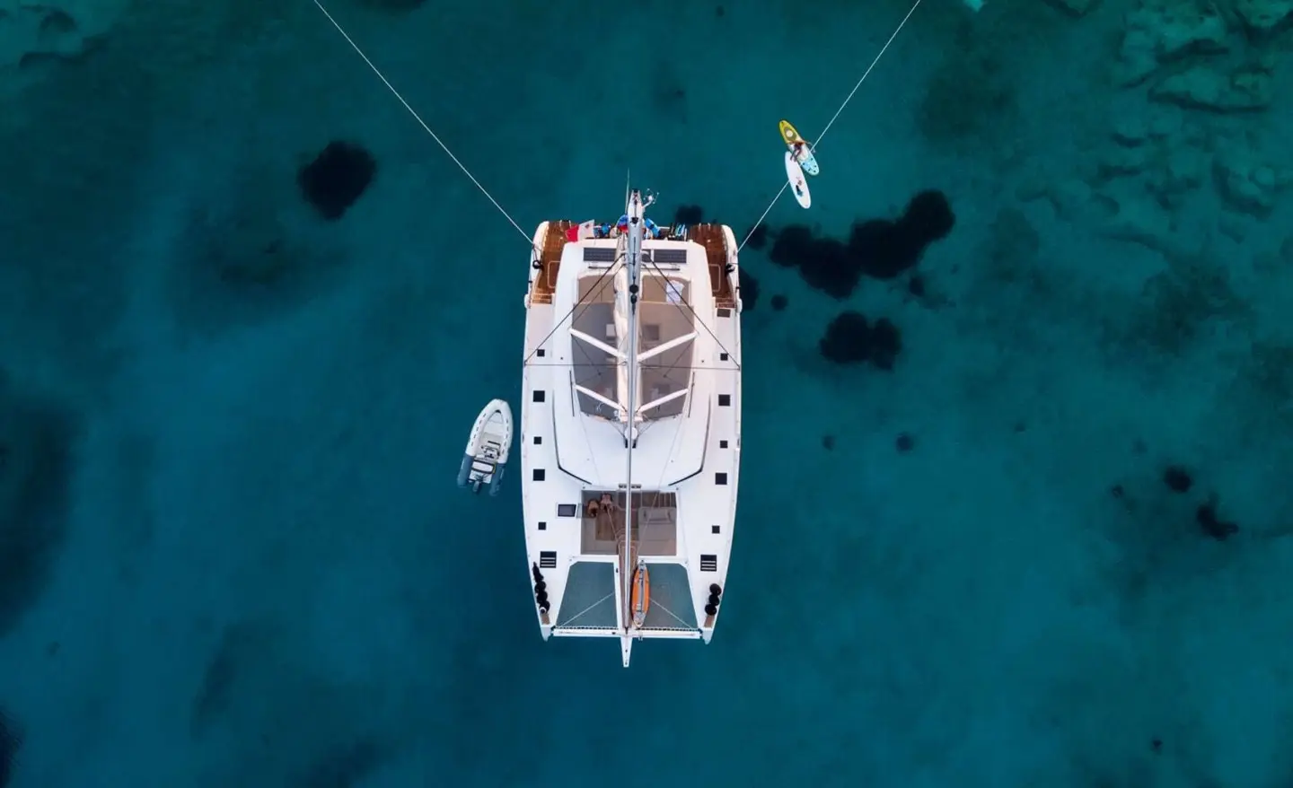 Aerial view of Serenissima yacht anchored in clear blue water, white hull, deck details visible