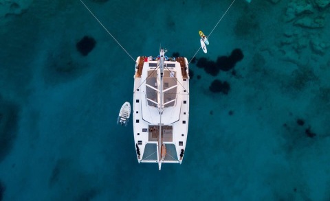 Overhead view of the Serenissima yacht anchored in clear blue water with a white hull