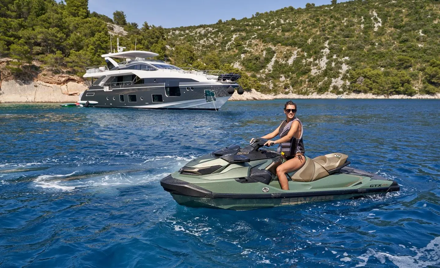 Yacht Aluminia Too anchored near rocky coastline with a person on a small motorized boat