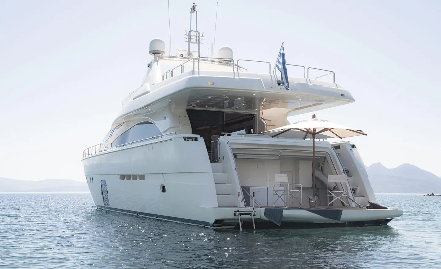 Lidia motor yacht anchored, stern platform extended over calm blue water