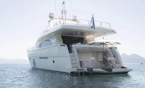 Lidia motor yacht anchored, stern platform extended over calm blue water