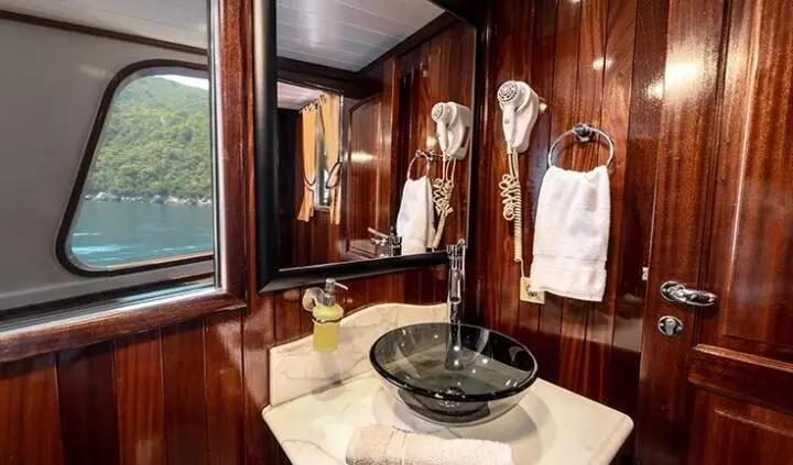Master cabin with king bed, wood paneling, and ensuite entry on Cesarica yacht