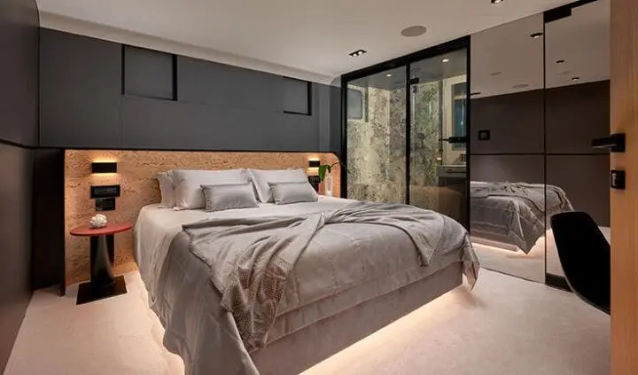 Master cabin with king bed, gray bedding, wood headboard, ensuite door, warm lighting