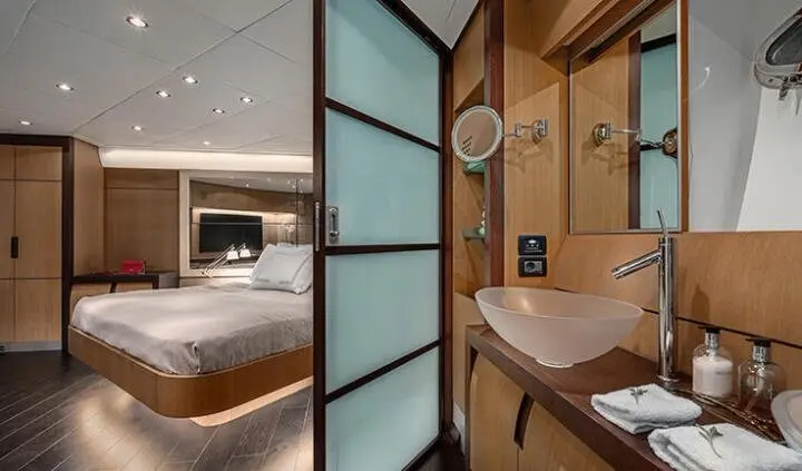 View of a yacht cabin with a large bed, ensuite bathroom, and wooden panels