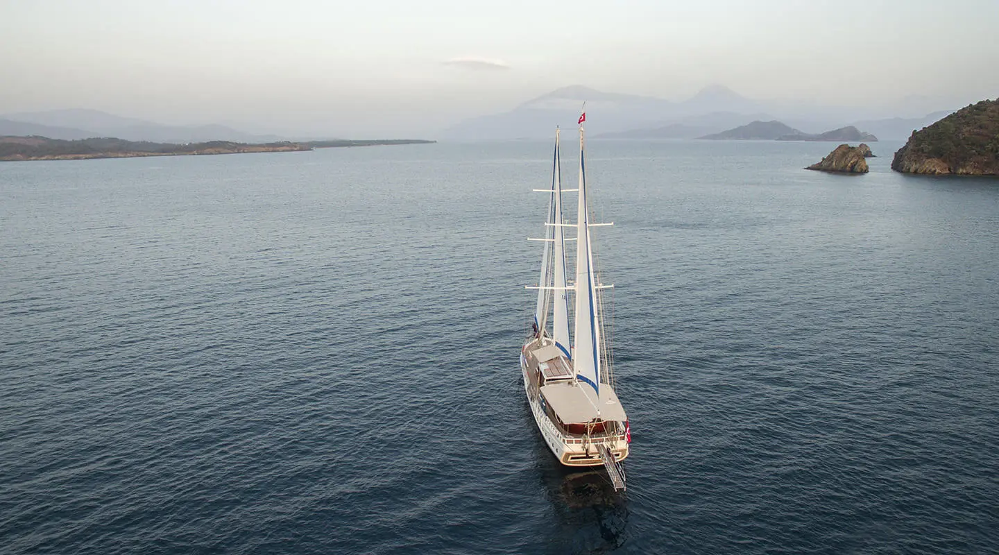 Kayhan 5 sailing yacht on calm blue sea with distant coastline and small islands