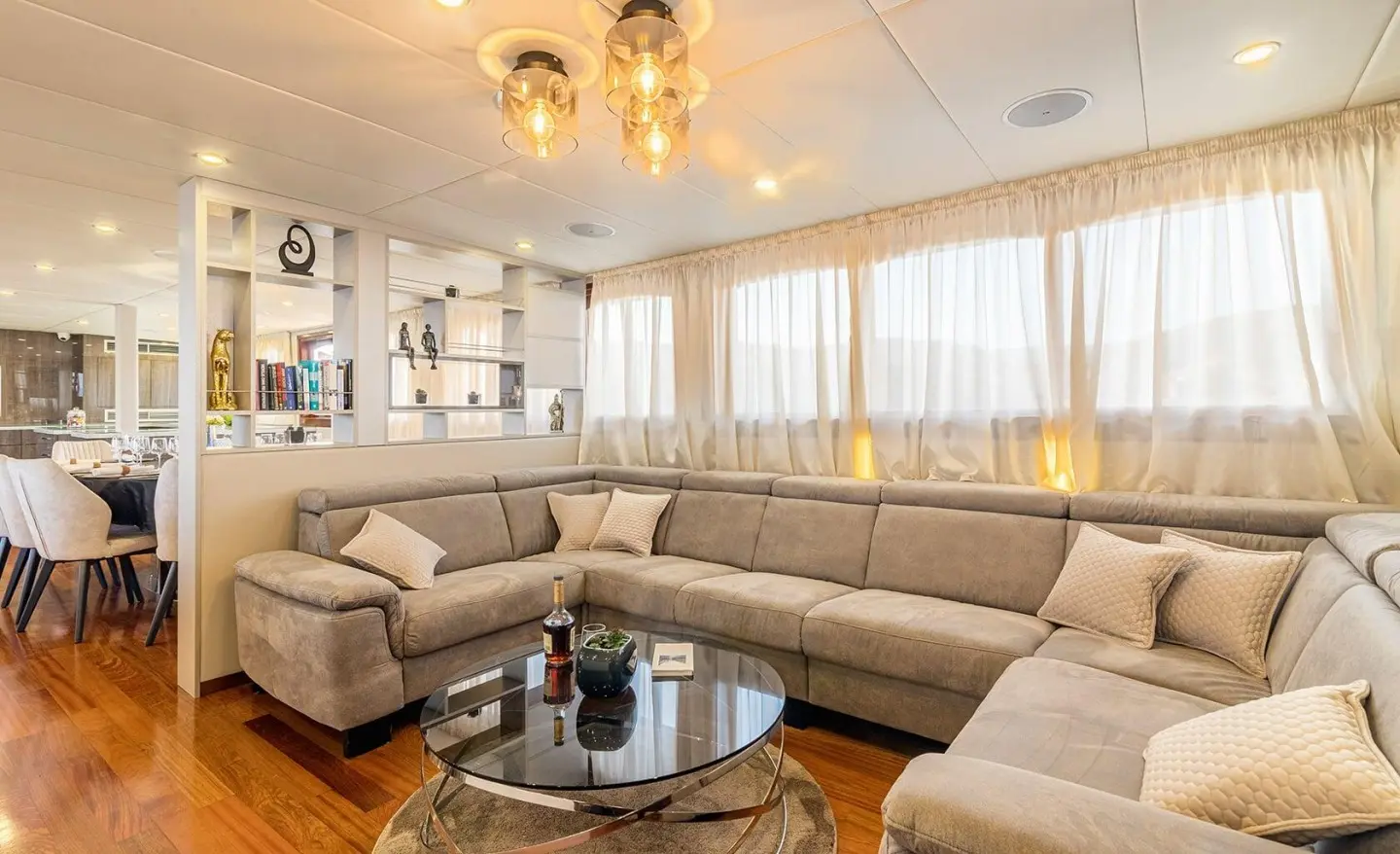 Interior lounge on Melody yacht with gray sectional sofa and glass coffee table