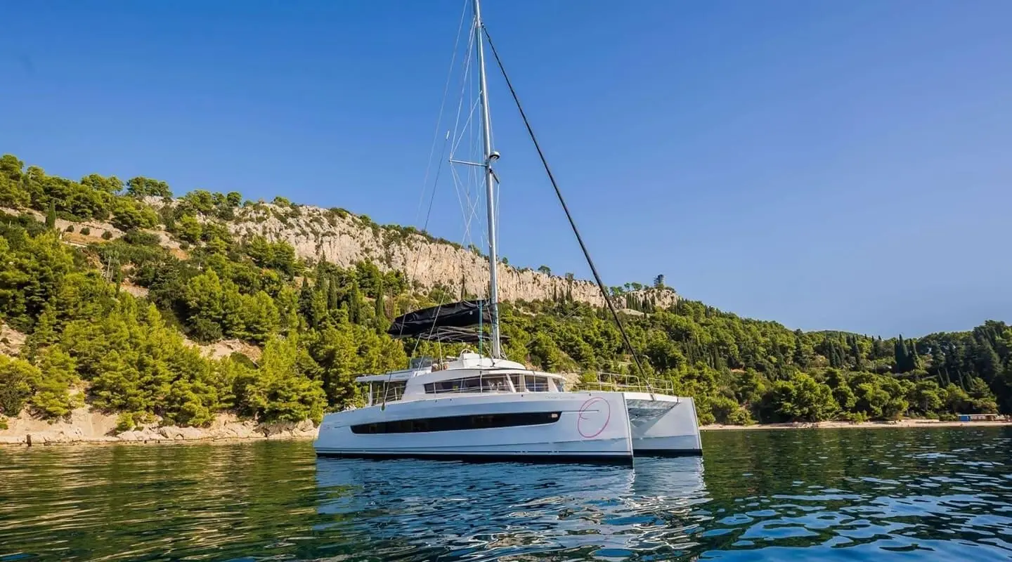 Ocean Lounge motor yacht anchored near rocky coastline under clear blue sky