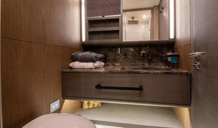 Master cabin with king bed and ensuite, wood tones, folded towel stack in background