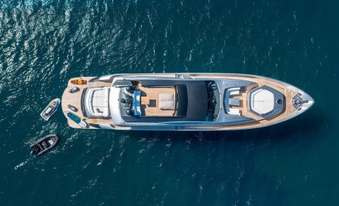 Top-down view of a yacht with teak deck and open seating area on the sunlit bow and aft