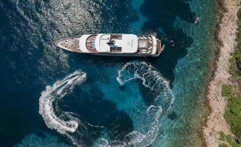 Aerial view of a sleek Riva luxury yacht anchored near rocky coastline