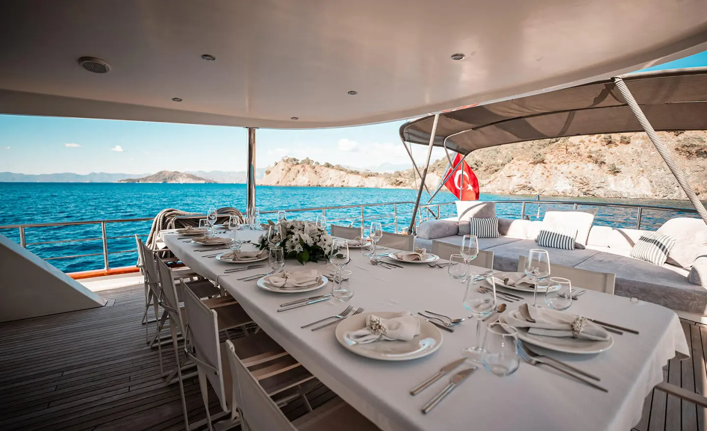 Aft deck dining setup on Queen Of Makri gulet, white tableware and chairs
