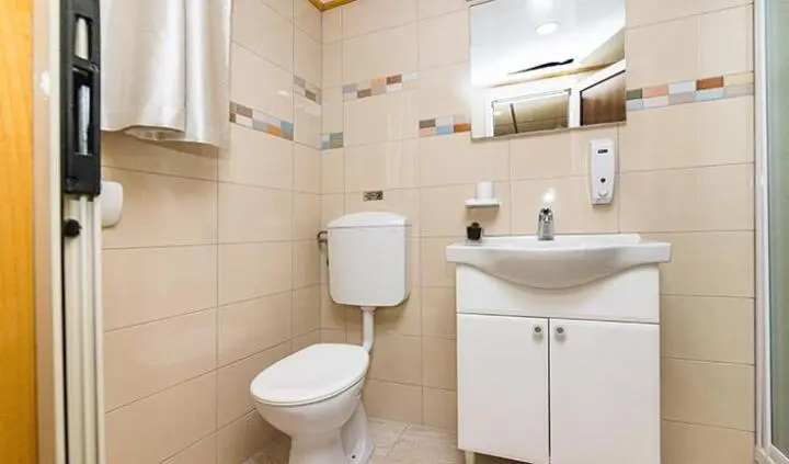 Small yacht cabin bathroom with white toilet, sink cabinet and mirror