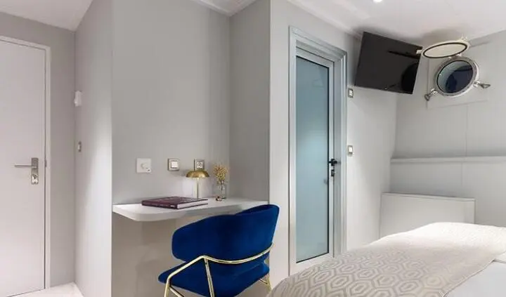 Master cabin with king bed, ensuite door, blue chair, and compact desk area