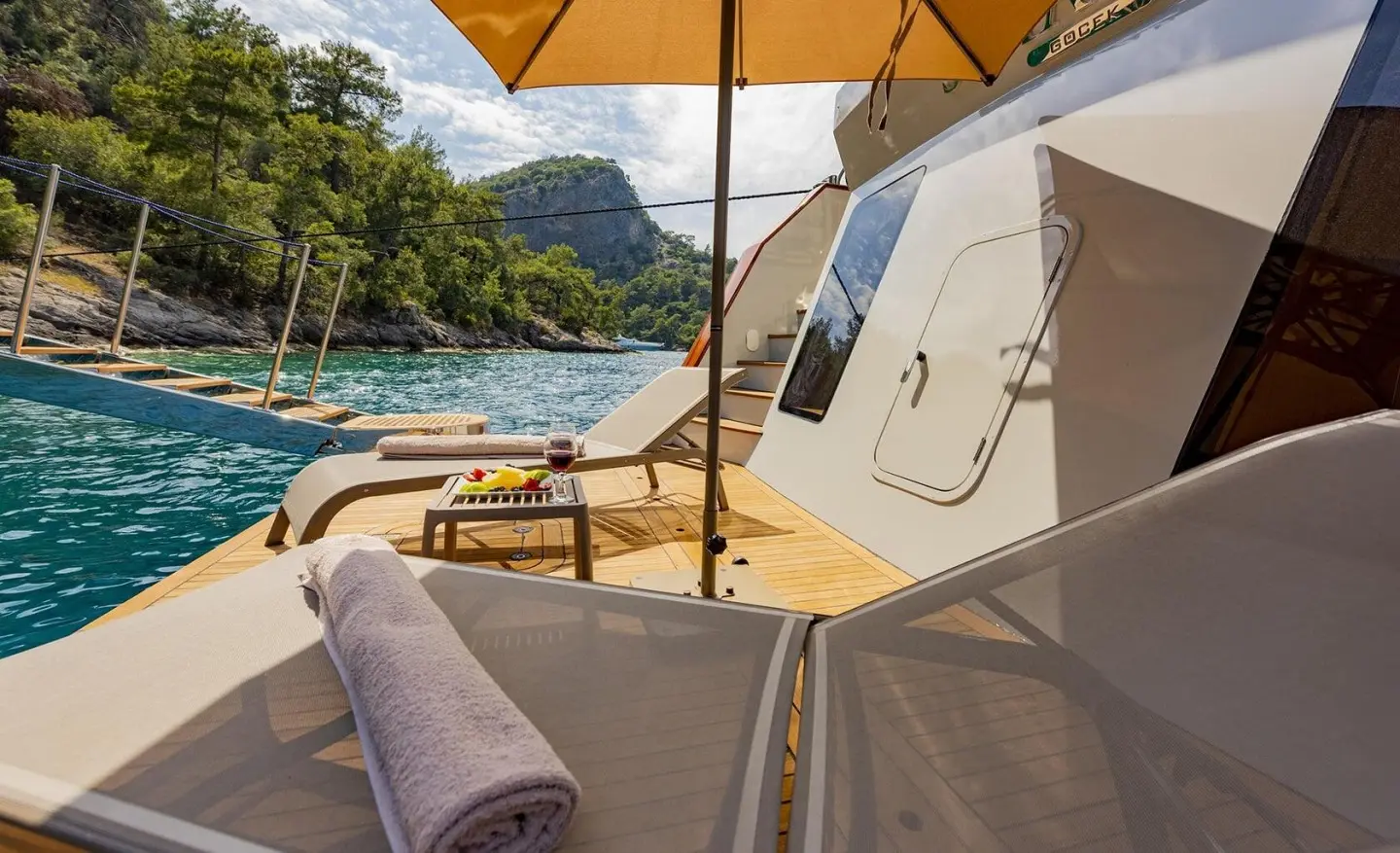 Simay M yacht deck view with sun loungers, orange shade, and sea through railing