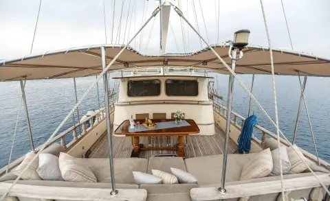 Gulet Faralya aft deck view with wheel, seating, blue hulls, and rigging