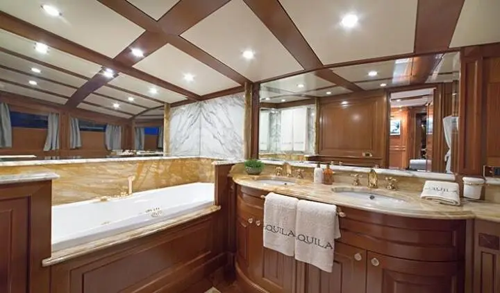 Aquila yacht master cabin with king bed, wood paneling, ensuite bathroom visible