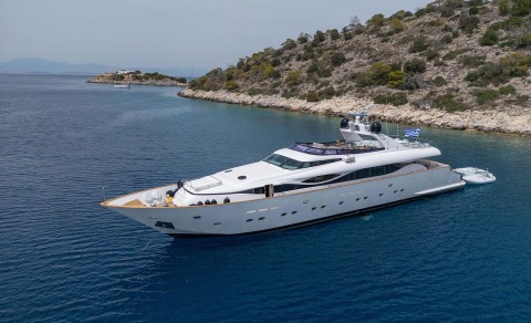 Pareaki II white motor yacht anchored in a calm blue sea near rocky coastline