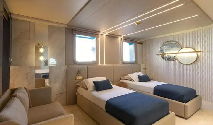 Twin cabin with two single beds, navy throws, wooden paneling, windows