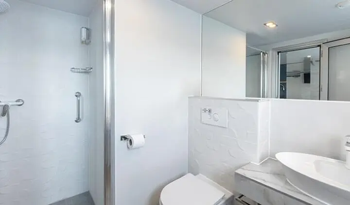 Yacht cabin bathroom with white fixtures, compact shower, and towel rack