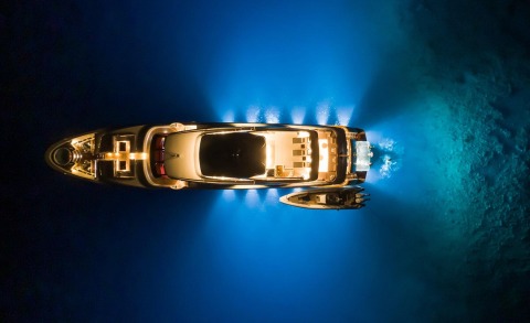 Night view of Takara One yacht illuminated on dark water, top-down