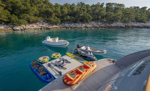 Glaros yacht moored near rocky shore with inflatable rings and a dinghy